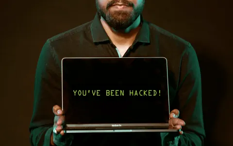 Hombre mostrando un portátil con un aviso de hackeo